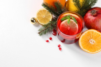 Photo of Christmas Sangria drink in glass, fir branches and fruits on white background, above view. Space for text