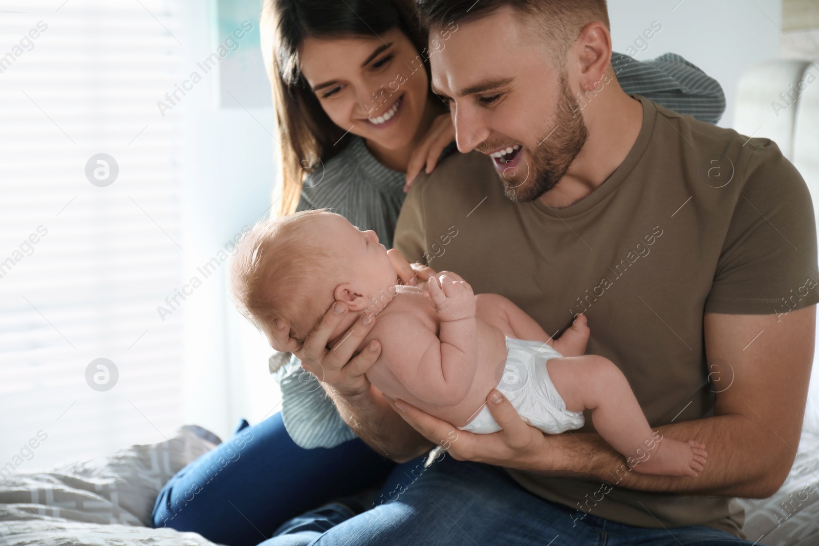 Photo of Happy couple with their newborn baby at home