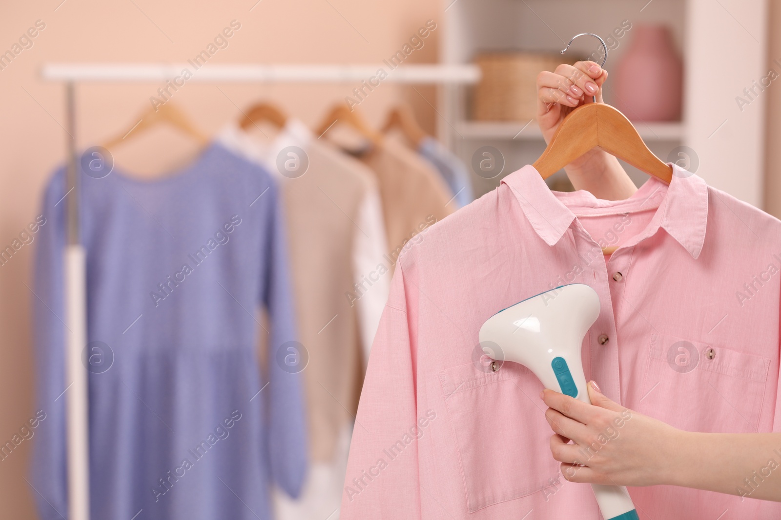 Photo of Woman steaming shirt on hanger at home, closeup. Space for text