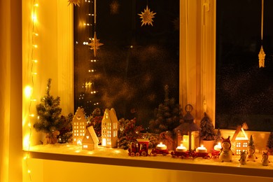 Photo of House shaped lanterns and Christmas decor on windowsill indoors