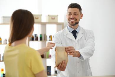 Photo of Pharmacist giving medicine to customer in drugstore