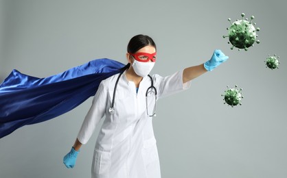 Image of Doctor wearing face mask and superhero costume fighting against viruses on light grey background