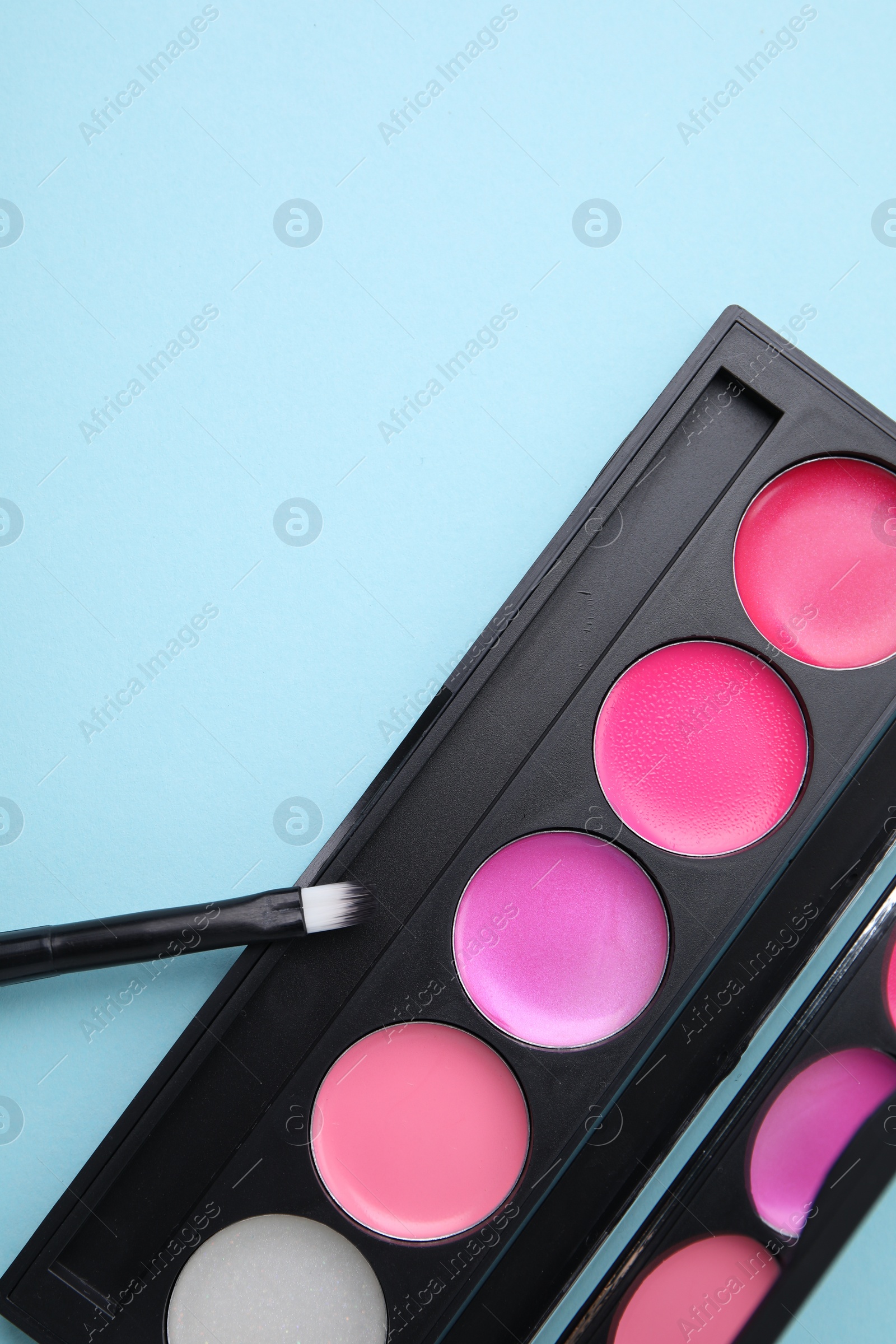 Photo of Colorful lip palette and brush on light turquoise background, flat lay