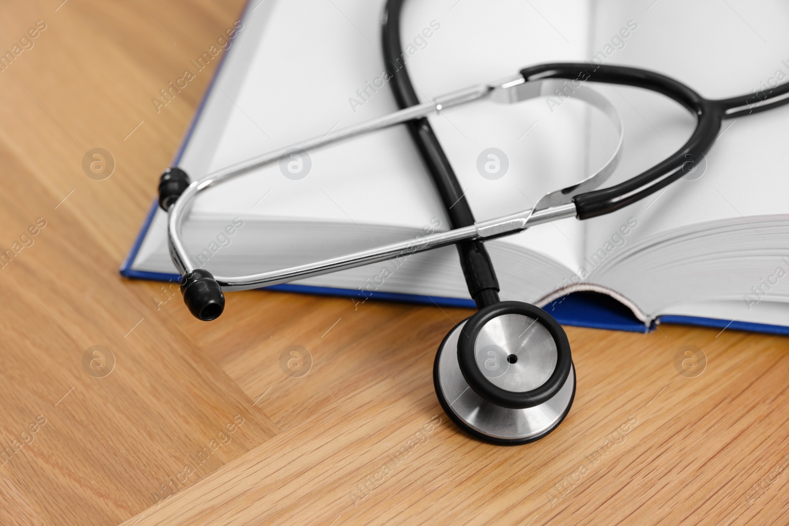 Photo of Book and stethoscope on wooden table, closeup