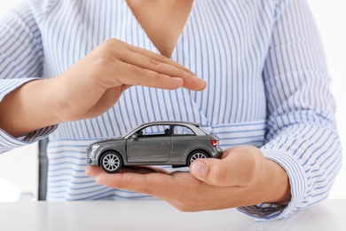 Female insurance agent holding toy car, closeup