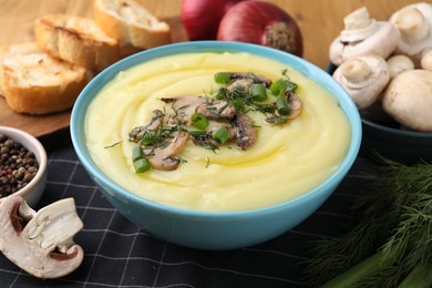 Photo of Bowl of tasty cream soup with mushrooms, green onions and dill on table