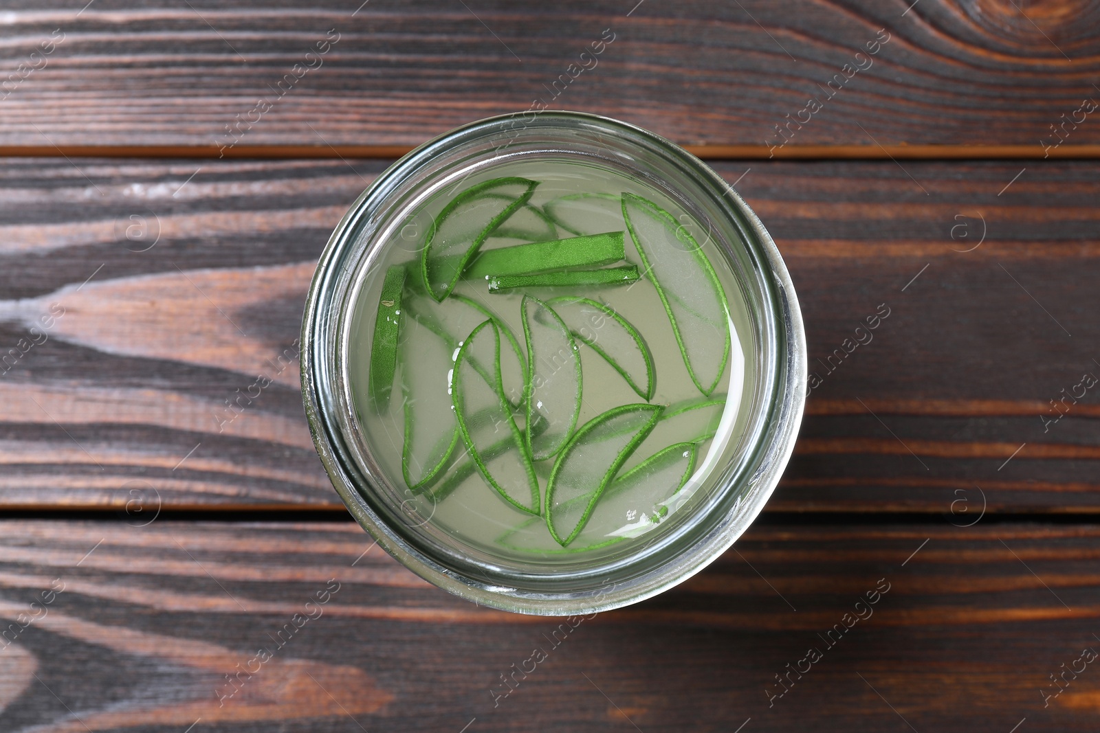 Photo of Fresh aloe juice in jar on wooden table, top view