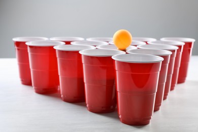 Photo of Plastic cups and ball for beer pong on white table