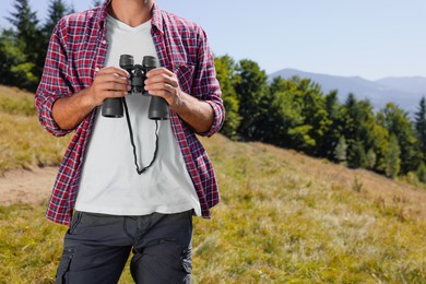 Man with binoculars outdoors on sunny day, closeup