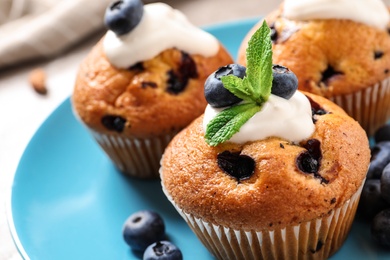 Photo of Platetasty muffins and blueberries on table, closeup