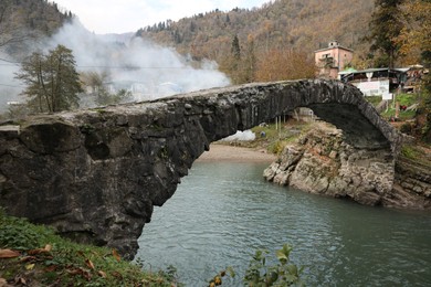 Photo of Adjara, Georgia - November 19, 2022: Picturesque view of stone arched bridge over Acharistskali river in mountains