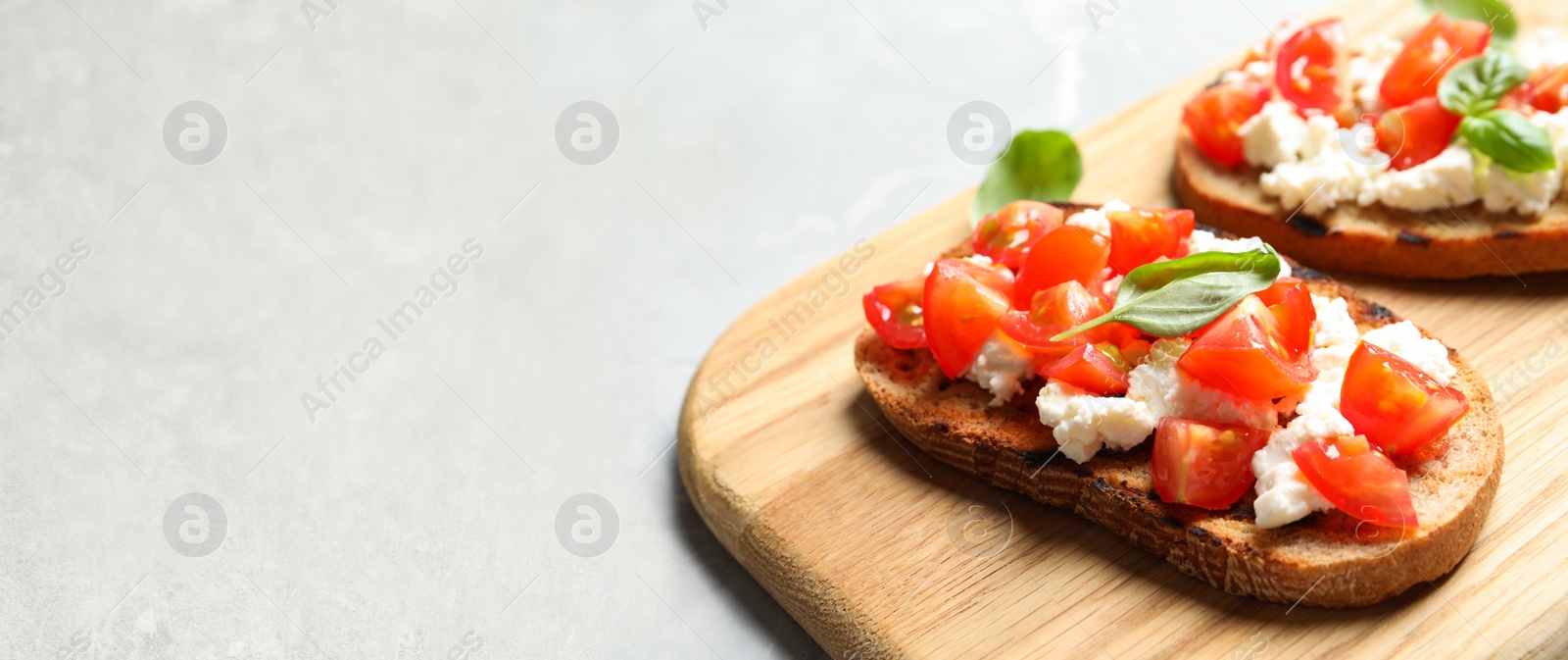 Image of Tasty bruschettas with tomatoes on light table, space for text. Banner design 