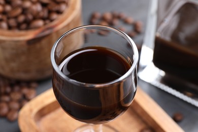 Photo of Glass of coffee liqueur on grey table, closeup