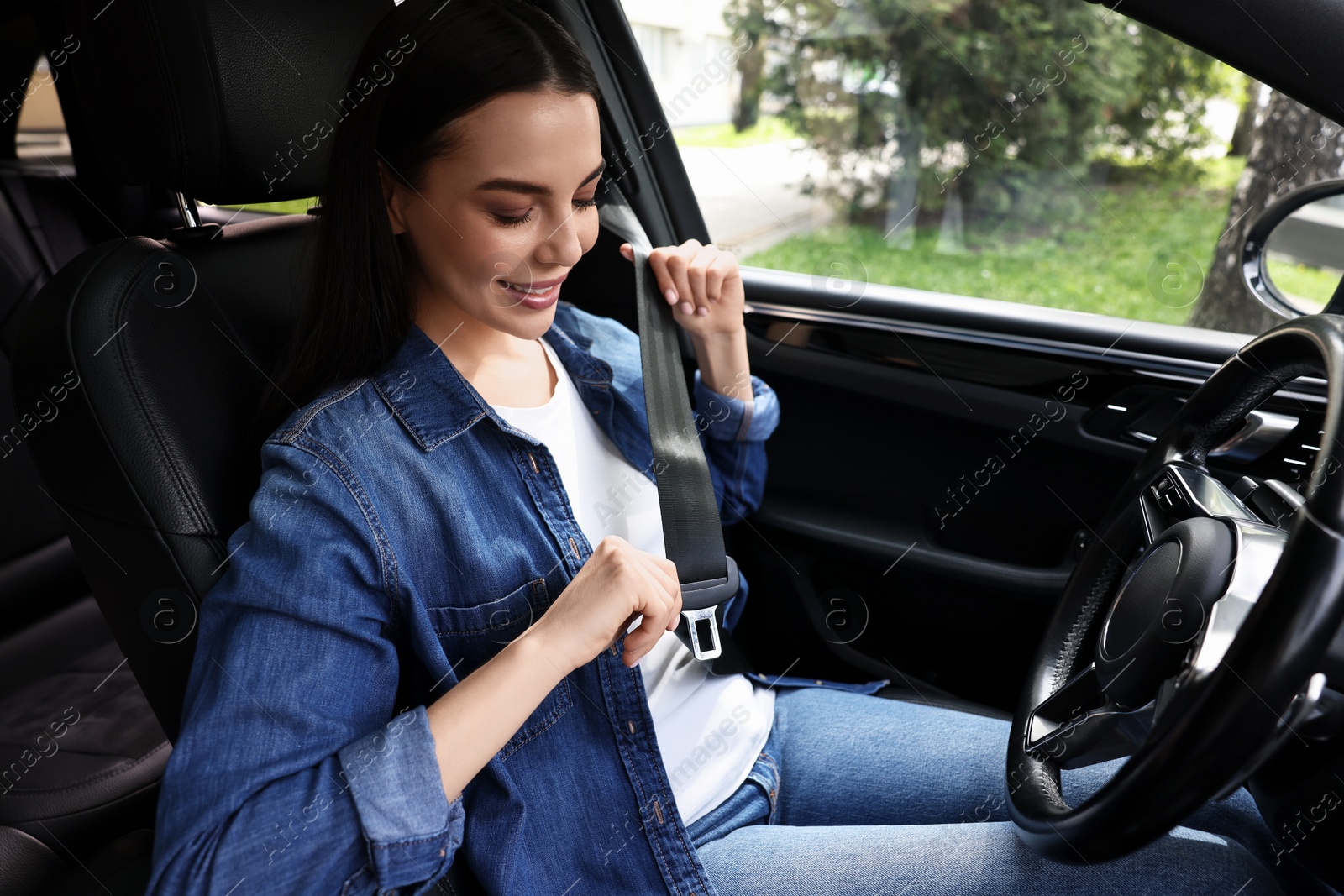 Photo of Woman fastening safety seat belt inside modern car