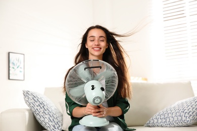 Photo of Woman with fan enjoying air flow at home. Summer heat