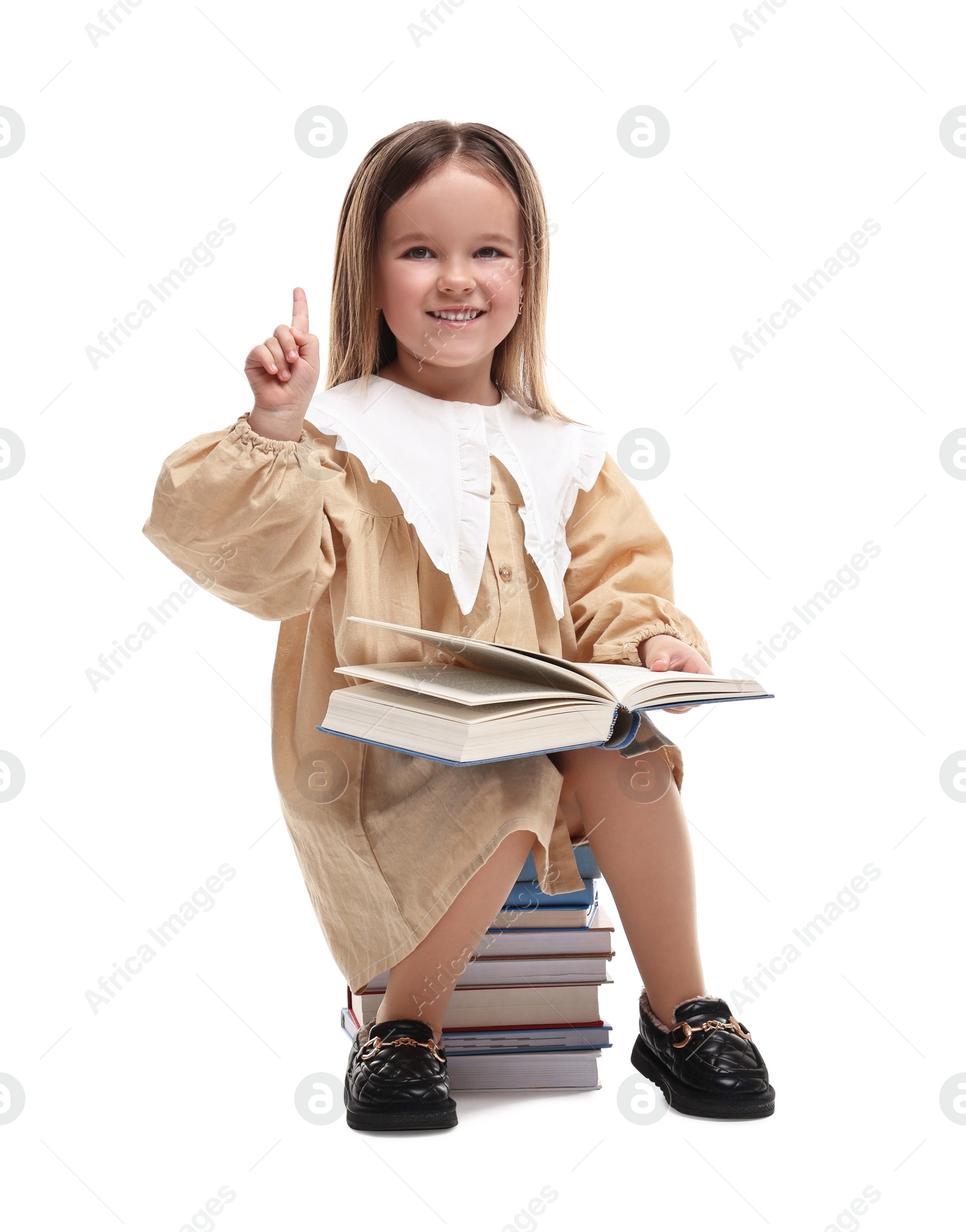 Photo of Cute little girl sitting on stack of books against white background