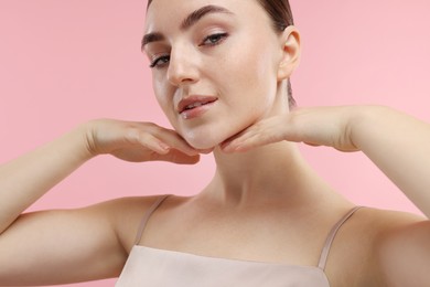 Beautiful woman touching her chin on pink background, closeup