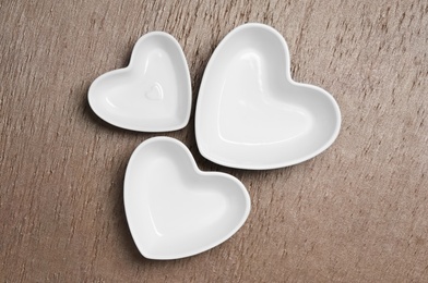 Heart shaped baking dishes on wooden table, flat lay. Cooking utensils