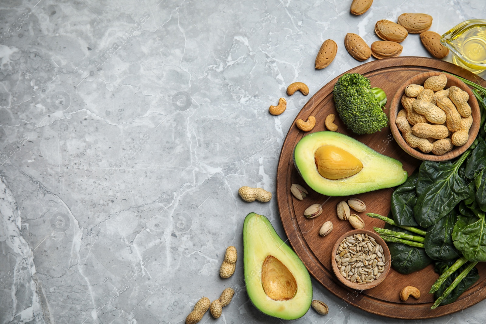 Photo of Different products rich in vitamin E on grey marble table, flat lay. Space for text