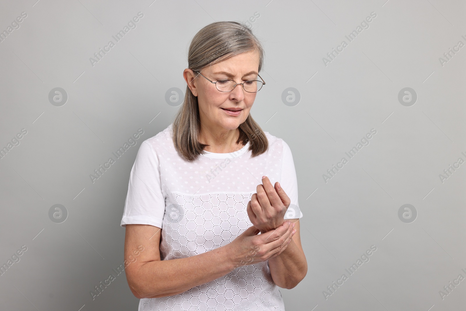 Photo of Arthritis symptoms. Woman suffering from pain in wrist on gray background
