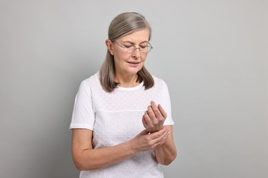 Arthritis symptoms. Woman suffering from pain in wrist on gray background