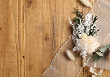 Photo of Stylish boutonniere and ribbon on wooden table, top view. Space for text