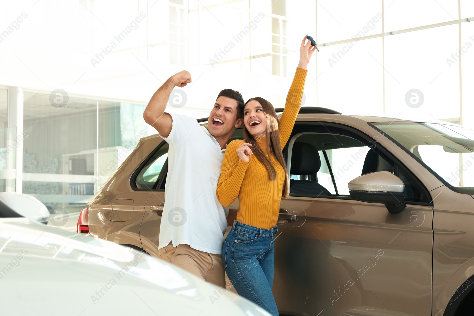 Photo of Happy couple with car key in modern auto dealership