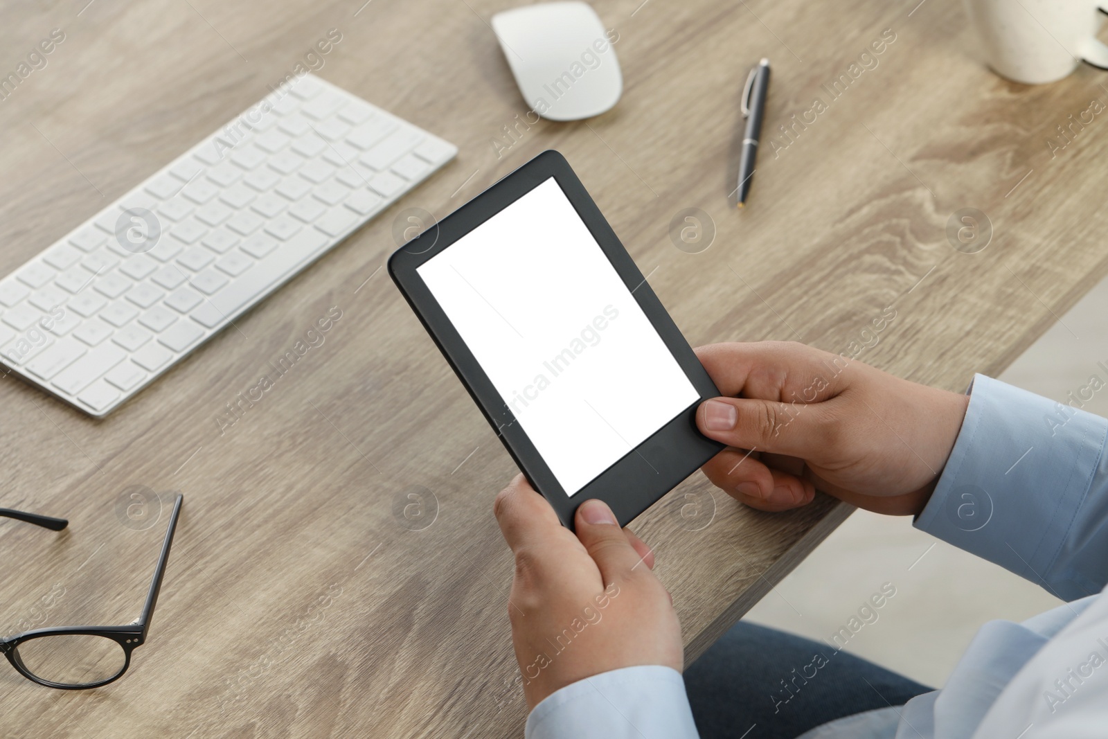 Photo of Man using e-book reader at wooden table, closeup