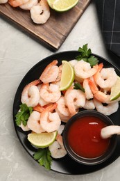 Photo of Tasty boiled shrimps with cocktail sauce, parsley and lime on light grey table, flat lay