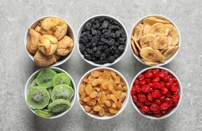 Bowls with different dried fruits on grey background, flat lay. Healthy food