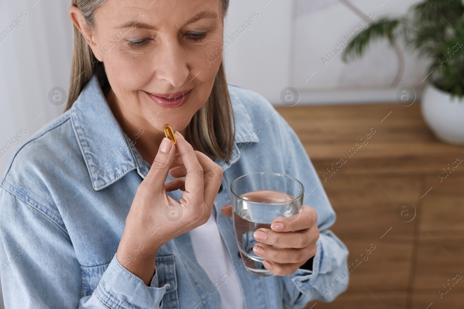Photo of Beautiful woman taking vitamin pill at home, closeup
