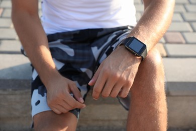 Photo of Man with fitness tracker after training outdoors, closeup