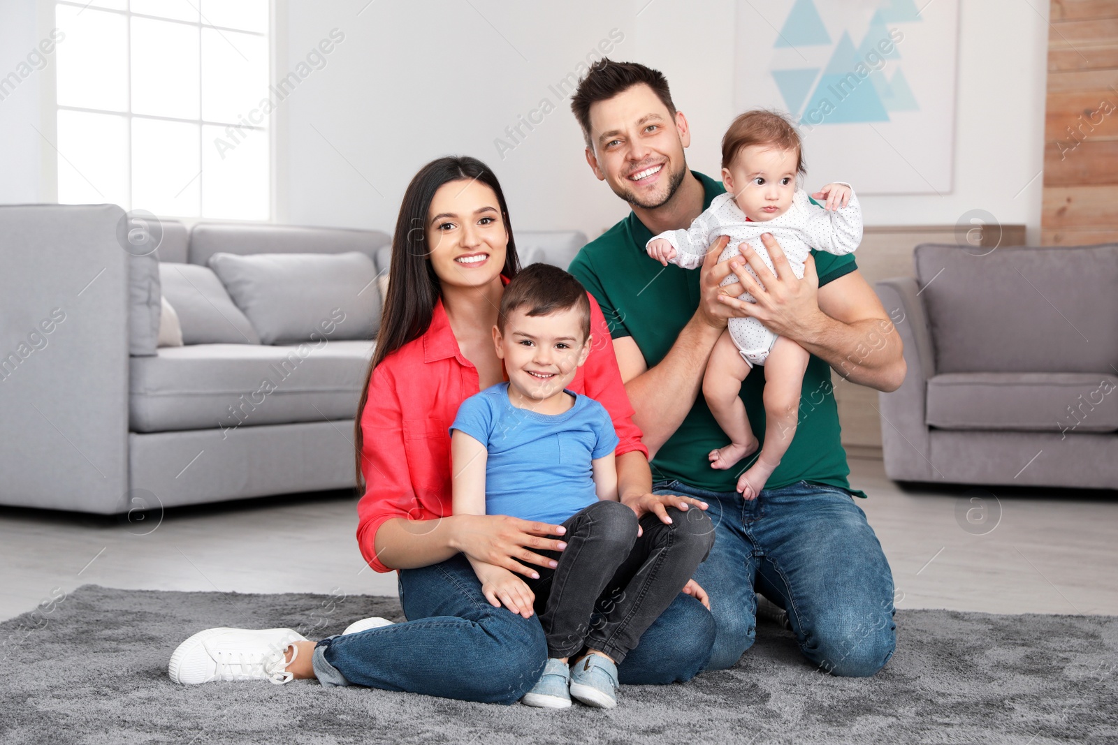 Photo of Happy parents and their cute children sitting on floor at home. Family time