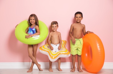 Photo of Cute little children with bright inflatable rings near color wall