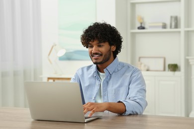 Handsome smiling man using laptop in room