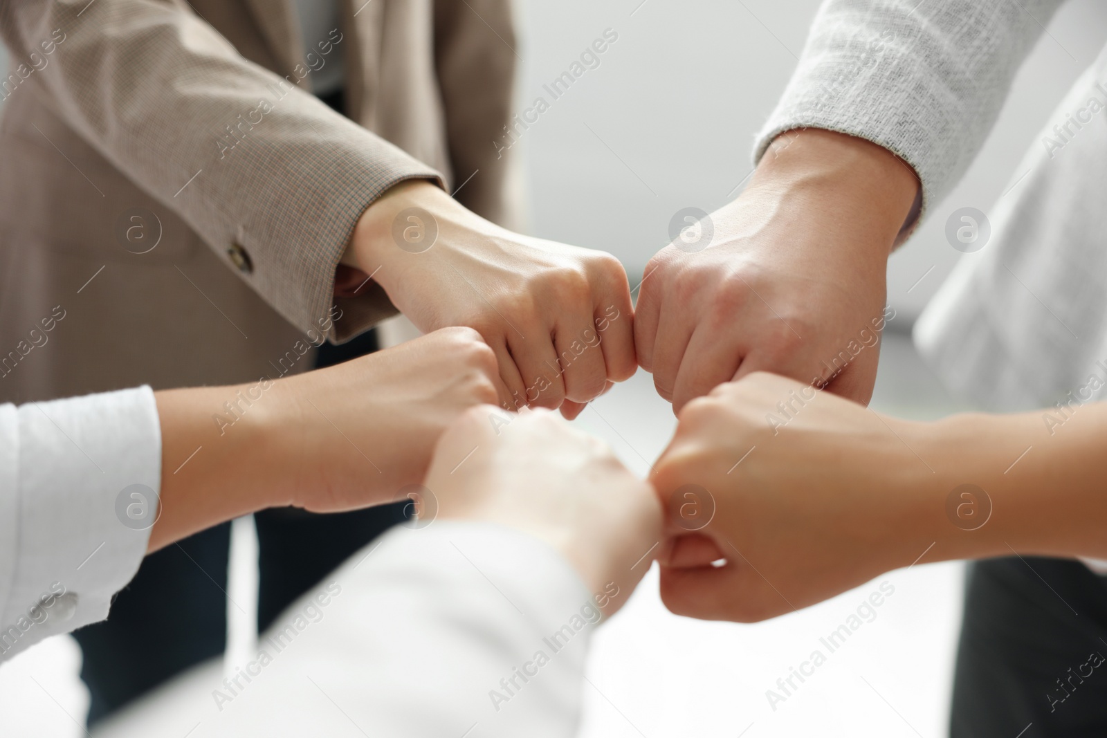 Photo of Group of people holding fists together indoors, closeup. Unity concept