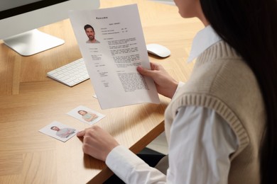Human resources manager reading applicant's resume in office, closeup