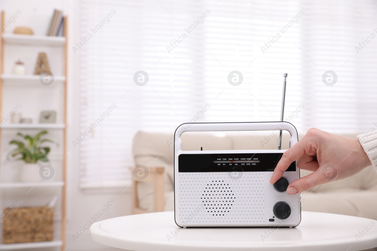 Photo of Woman turning volume knob on radio at home, closeup. Space for text