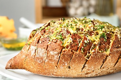 Photo of Tasty homemade garlic bread with cheese and herbs on plate, closeup