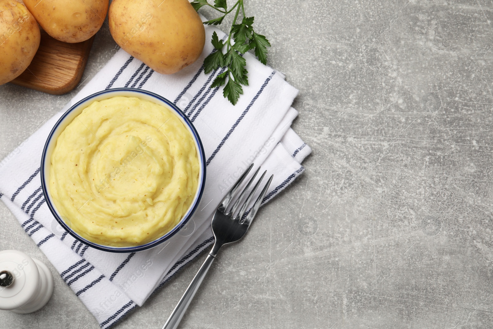 Photo of Bowl of tasty mashed potatoes served on grey marble table, flat lay. Space for text