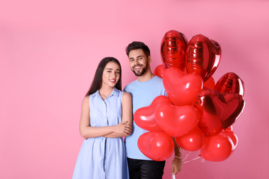 Photo of Lovely couple with heart shaped balloons on pink background. Valentine's day celebration