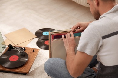 Photo of Man with collection of vinyl records near turntable at home