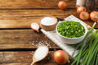 Photo of Chopped green onion in bowl on wooden table, space for text
