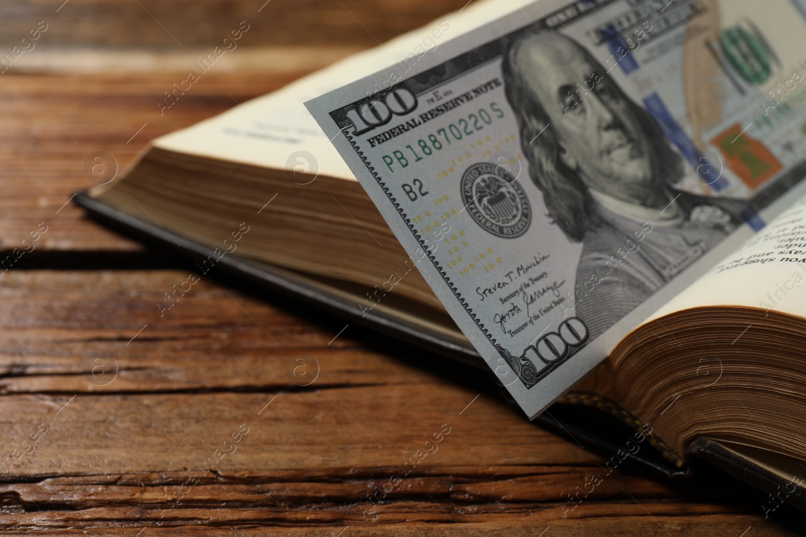 Photo of Open Bible with money on wooden table, closeup