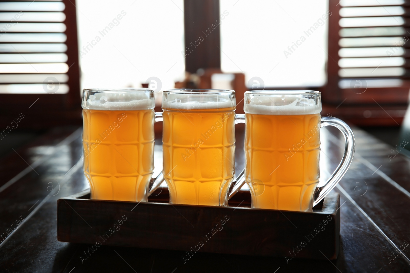 Photo of Glasses of tasty beer on wooden table in bar