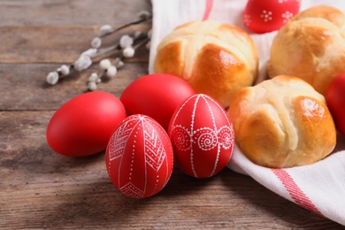 Photo of Red painted Easter eggs and buns on wooden table, closeup