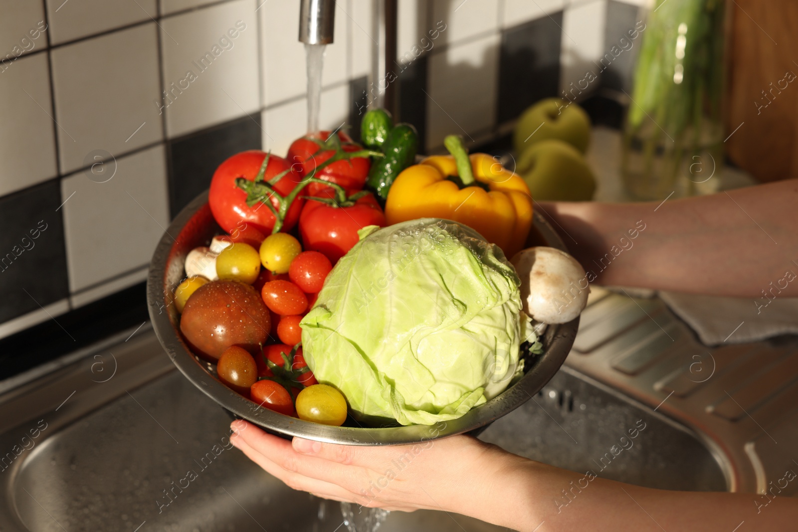 Photo of Woman washing different vegetables in metal colander, closeup