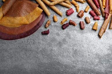 Photo of Delicious fruit leather rolls on grey table, flat lay. Space for text