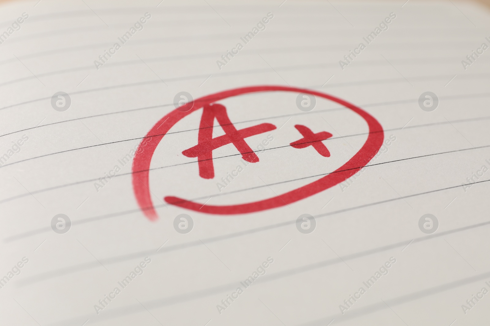 Photo of School grade. Red letter A with plus symbol on notebook paper, closeup