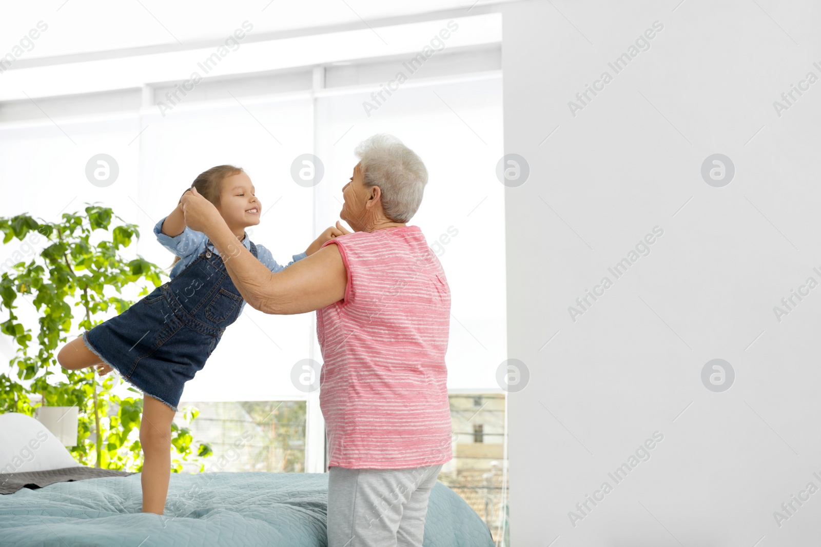 Photo of Cute girl and her grandmother playing together at home